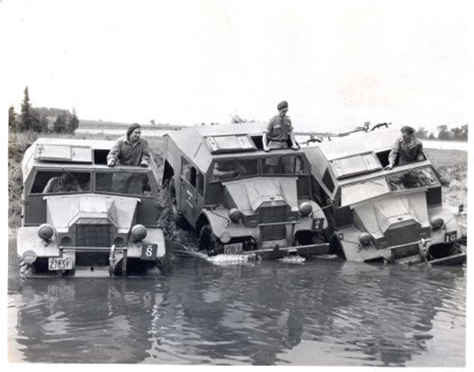 Men driving military vehicles through a river.