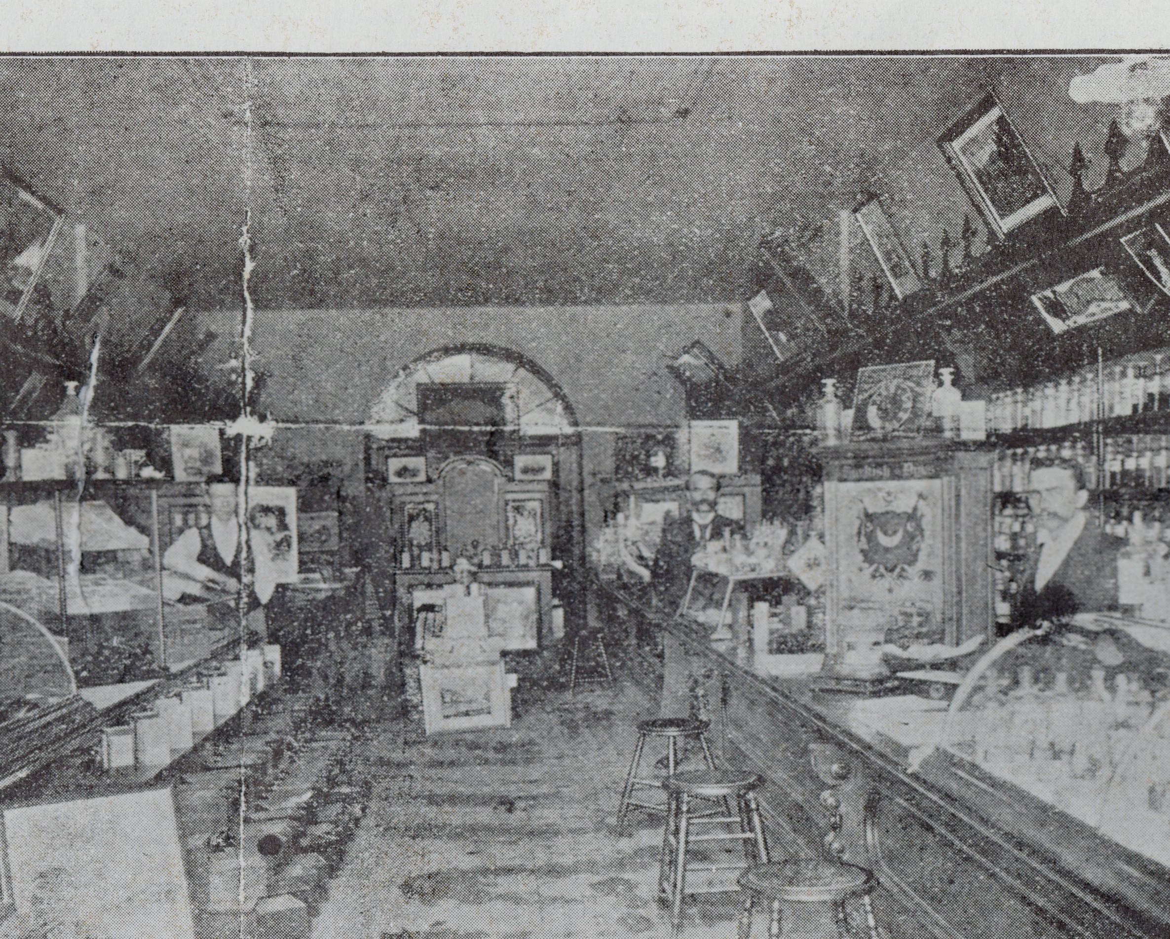 Photo showing the interior of McCollom's drug store. Two men stand on either side of the store behind counters. Bottles, cans, and other containers and materials for sale line shelves and are displays on tables.